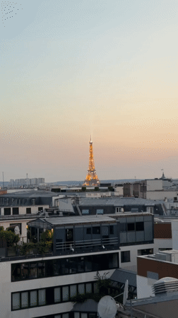 Rooftop drinks in Paris with the Eiffel Tower lit up at sunset.