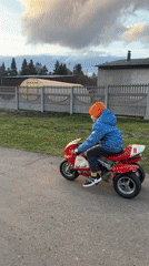 Child rides red three-wheeled motorcycle in rural Russia