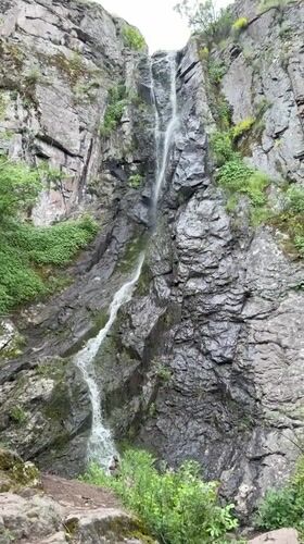 Tourists visit waterfall in Ustina, Bulgaria amid overcast skies