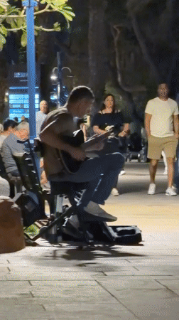 Street musician performs acoustic guitar in Eilat evening