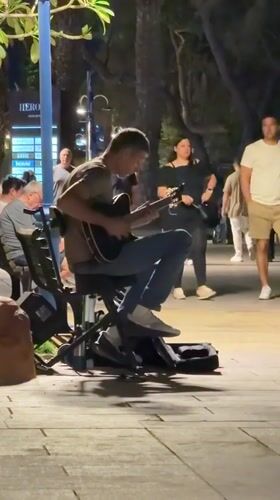 Street musician performs acoustic guitar in Eilat evening