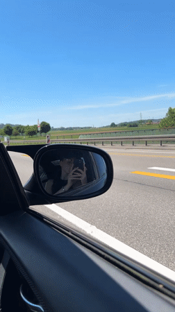 Woman takes selfie in car mirror on German highway