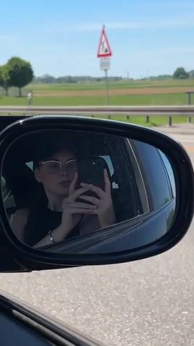Woman takes selfie in car mirror on German highway