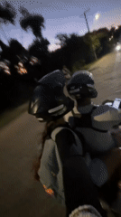 Three people share scooter ride at dusk in Búzios