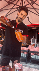 Man pours beer under red umbrella in Konyaaltı