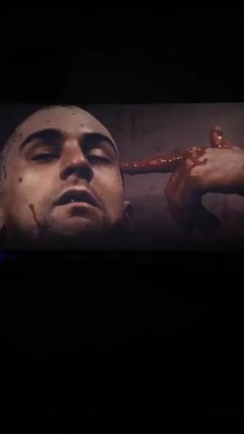 A close-up shot features a bloodied man, resembling Robert De Niro, with short dark hair, looking upward and slightly to the left. His right hand, also covered in blood, has its index finger pressed against his right temple, mimicking a gun. Blood streaks are visible on his face and neck. He takes a slow, deep breath. The background is dark and indistinct.