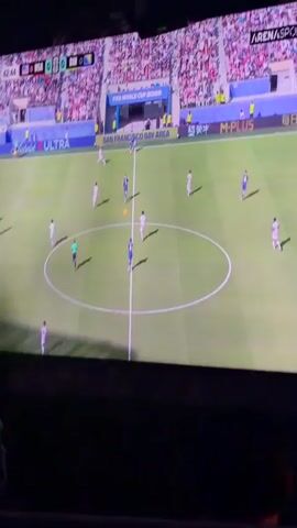 The video shows a television screen displaying a soccer match. The scoreboard indicates the teams are USA and CRO (Croatia), with the score 0-0. Players in white and blue jerseys are on the green field, some running and some in defensive positions. A referee in a black uniform is also visible. Spectators are in the stands, wearing a mix of white and red clothing. The stadium has advertisements for "FIFA WORLD CUP 2026" and "SAN FRANCISCO BAY AREA." The broadcast channel appears to be "ARENASPORT." The action is focused on the center circle of the field.