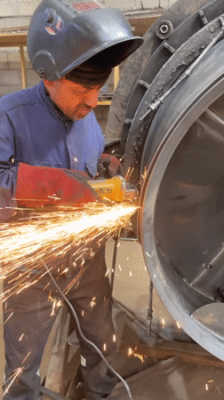 Worker grinds metal with safety gear in Tomba, Montenegro