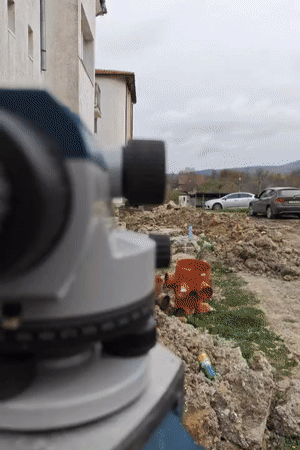 Surveyor measures construction site with yellow backhoe in Tsarevo