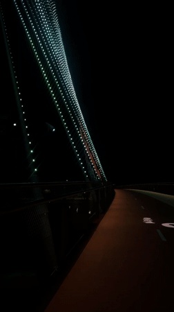 Skateboarder in purple Crocs crosses illuminated Perth pedestrian bridge