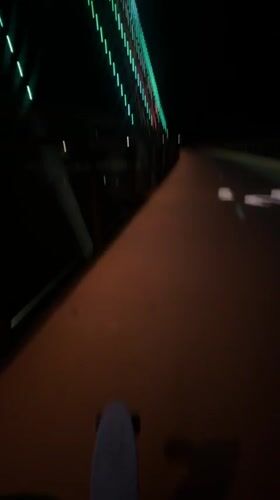 Skateboarder in purple Crocs crosses illuminated Perth pedestrian bridge
