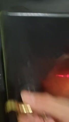 The video shows a close-up view inside a fireplace. The fire is burning low, with glowing embers and a few small flames dancing on top of a charred log. Ash and partially burnt wood are visible on the bottom of the fireplace. The interior of the fireplace is dark, with a red glow emanating from the embers. The camera is relatively still, providing a steady view of the fire.