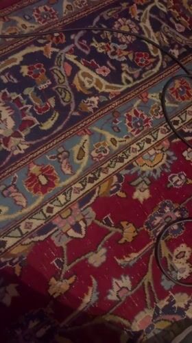 Red oriental rug with floral patterns, black cable across it