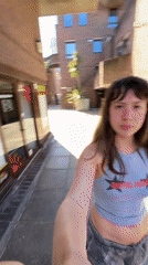 Woman in branded crop top walks through London courtyard