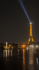 Eiffel Tower glowing at night, beacon sweeping the Paris sky