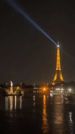 Eiffel Tower glowing at night, beacon sweeping the Paris sky