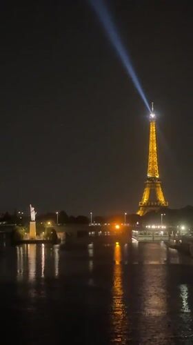 Eiffel Tower glowing at night, beacon sweeping the Paris sky