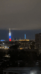 Communications tower displays patriotic lighting in nighttime cityscape