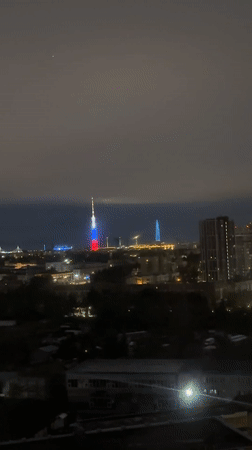 Communications tower displays patriotic lighting in nighttime cityscape