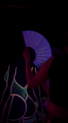 Person waves glowing fan near neon artwork in Varna