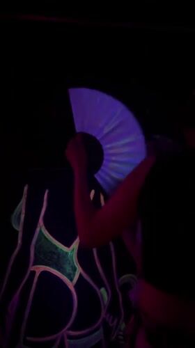 Person waves glowing fan near neon artwork in Varna