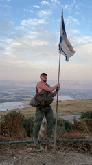 Man displays Israeli flag atop hill in northern Israel