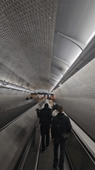 Pedestrians use moving walkway in textured Paris corridor