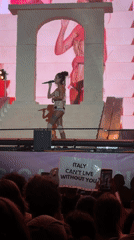 Live stage performance with bold visuals and a pink backdrop