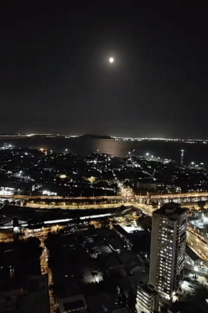 Full moon illuminates Mumbai's nighttime cityscape from elevated views