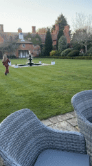 Girl in magenta runs toward fountain on Suffolk estate