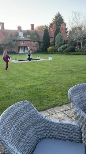 Girl in magenta runs toward fountain on Suffolk estate