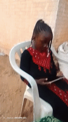 Girl uses tablet, phone while seated outdoors in Nigeria