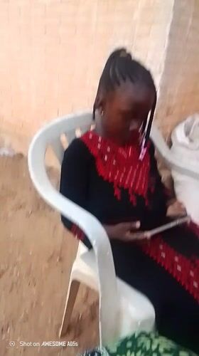 Girl uses tablet, phone while seated outdoors in Nigeria