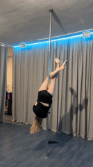 Woman practices pole dancing moves at studio