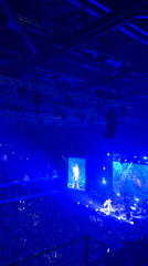 Arena concert features white-suited performer with pyrotechnics, blue lighting