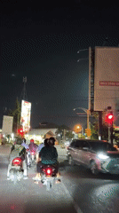 Surakarta night traffic: motorcycles at lights, billboards glowing