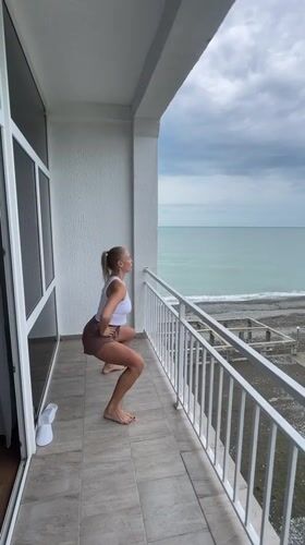 Woman conducts morning workout routine on seaside balcony in Abkhazia