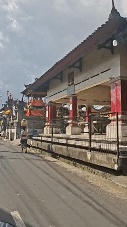 Balinese temple street scene with penjors, offerings, and sacred architecture