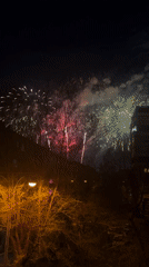 Nighttime fireworks display lights up urban neighborhood sky