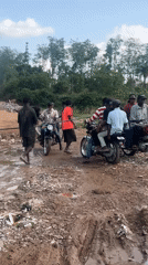 People gather with motorbikes on muddy road in Abuja