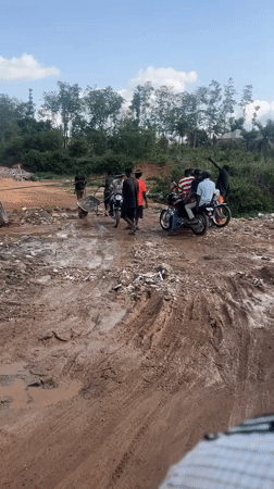 People gather with motorbikes on muddy road in Abuja