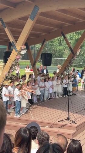 Children perform on stage in Serbia wearing white, hats