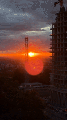 Urban sunset silhouettes industrial structures across city skyline