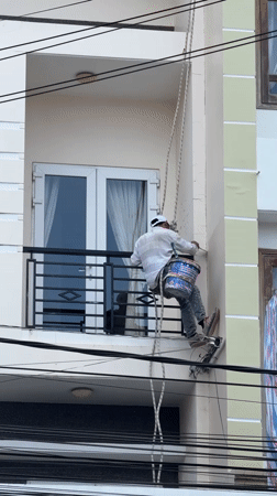 Rope-suspended painter works on multi-story building in Da Lat