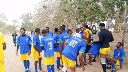 Soccer players gather after game on dirt field in Minna