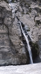 Waterfall crashes down rocky cliff into turbulent river, Shansha