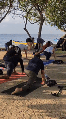 Yoga class and Balinese memorial service share Sanur Beach