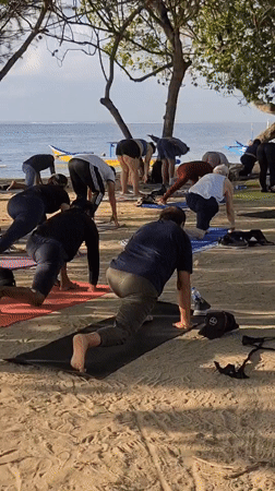 Yoga class and Balinese memorial service share Sanur Beach