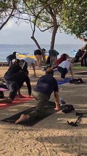 Yoga class and Balinese memorial service share Sanur Beach