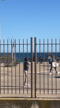 Girl roller skates along fence in Badalona, Spain